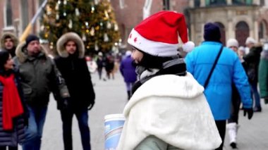 KRAKOW, POLAND - 12 / 01 / 2022: Krakow 'un merkez meydanında Kar Kızı' nın Noel kostümlü bir kız çocuğu, yoldan geçenlerden Noel ve yeni yıl arifesinde bağış topluyor.