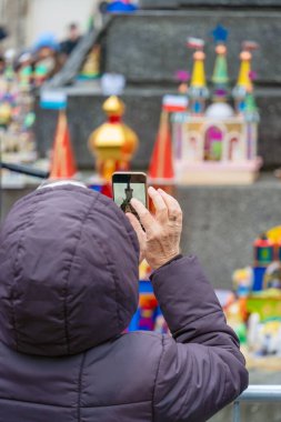 Krakow 'un merkezinde geleneksel bir el sanatları sergisi olan Noel arifesinde Krakow manzaralı minyatür modellerin yıllık yaratıcı yarışmasını akıllı telefondan çeken bir kadın görülüyor.