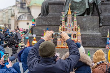 Seyirciler akıllı telefonlardan çekim yapıyor. Şehir sokaklarında halka açık bir etkinlik. Çok sayıda insan arasında. Shopka yarışması - Krakow 'un merkezinde geleneksel bir el yapımı maketler sergisi