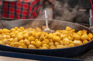 Noel ve Krakow 'daki yeni yıl pazarında şehir sokaklarında büyük bir dökme demir tavada soyulmuş patatesler pişiriliyor. Otantik Polonya aşçılık gelenekleri