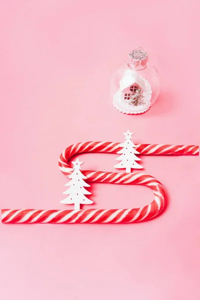 Stock image Minimalistic christmas pattern, new year holiday candy canes with white fir trees, house in christmas tree toy on pink background, abstract flat lay for background and greeting card. Copy space