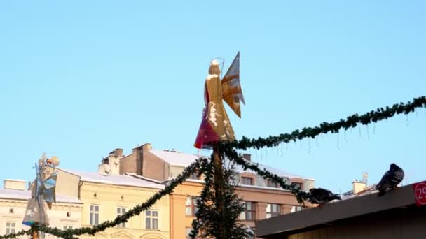 雪の降る冬の日には青空を背景に天使の姿をしたガーランドが町の広場に設置されます ポーランドのクリスマスの伝統 — ストック動画