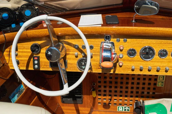 Authentic vintage design of the interior and controls in the cockpit of a sea boat on a sunny day. Real white steering wheel of a sea cab boat in Venice. Voyages and adventures at sea
