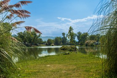 Yaz tatili ve dinlenme güzel bir göl, motorlar, bisikletler ve balıkçı oltaları mavi gökyüzünün altında arka planda, otantik bir insan dengesi ve doğa, ekolojik refah