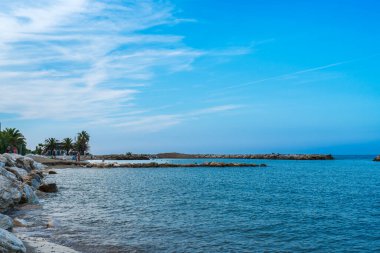 Sakin deniz yüzeyinde mavi gökyüzü, palmiye ağaçları yakınında bir grup tatilci, İtalya 'da deniz sakin, güzel deniz manzaralı, sahil yaz tatili, otantik sürdürülebilir gelişim, kopyalama alanı