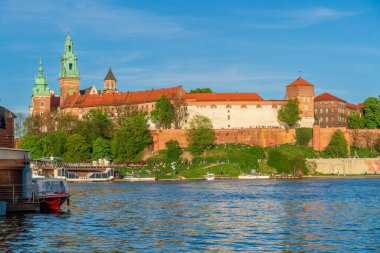 Wawel Kraliyet Şatosu bir tepenin üstünde su birikintisinin yanında, güzel bir şehir manzarası, fotoğraf bir tekneden çekilmiş, panoramik bir resim, Polonya 'nın eski Avrupa şehri Krakow, arka planda ortaçağ kalesi.