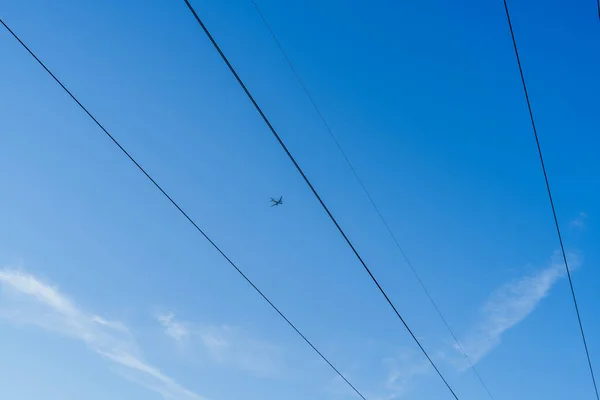 飞机在天空中高高地飞越电力线 清晰线 蓝天梯度 飞机与高压电塔交叉口 连接线与交错路径 低视点 — 图库照片
