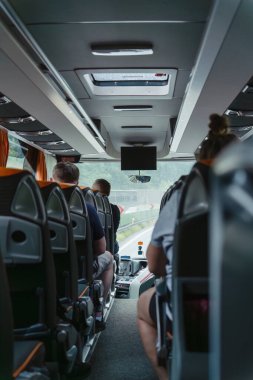 Otobüsün içinde yağmur sırasında yolcu koltukları, yolcu otobüsünün ön camında yağmur damlaları, otobüs şoförünün gösterge paneli, bulutlu bir turist yolculuğu...