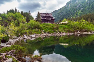 Polonya Tatra Ulusal Parkı 'nda Morskie Oko Gölü kıyısında Chalet. Göl dağlarda yer alır ve çevresindeki tepeleri ve ağaçları yansıtır. Bu görüntü doğa ve seyahat için mükemmel.