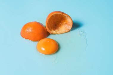 Canlı, yaratıcı bir görüntü, turkuaz bir arka planda içinden yumurta sarısı akan mandalinanın iki yarısını gösteriyor. Yaratıcılık, tazelik ve doğal ürünlerle ilgili kavramlar için idealdir.