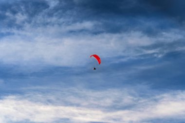 Bir paraglider dramatik bulutların zemininde özgürce süzülür, özgürlük ve macera kavramını somutlaştırır. Uçsuz bucaksız gökyüzü uçmanın heyecanını vurgular. Ekstrem spor temaları için ideal