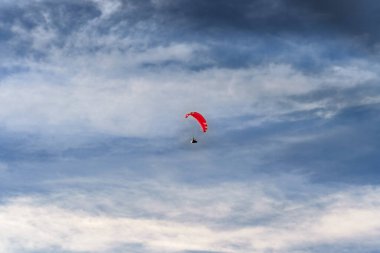 Bir paraglider dramatik bulutların zemininde özgürce süzülür, özgürlük ve macera kavramını somutlaştırır. Uçsuz bucaksız gökyüzü uçmanın heyecanını vurgular. Ekstrem spor temaları için ideal
