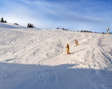 Kayakçılar temiz mavi gökyüzünün altında el değmemiş bir yamacı oyup kış sporları ve macera kavramını somutlaştırıyorlar. Seyahat, eğlence ve spor teması için ideal.