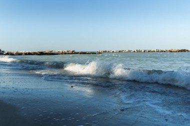 Sahil dalgaları yumuşak dalgalar ve berrak gökyüzü ile deniz sahillerinde, barışı ve 2024 doğayla yeniden bağlantı trendini temsil ediyor.