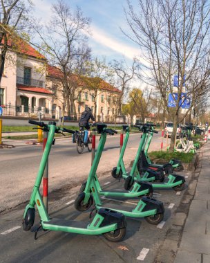 Şehir kaldırımında düzgün park etmiş bir dizi elektrikli scooter çevre dostu şehir ulaşımını ve ortak hareketlilik kavramlarını simgeliyor..