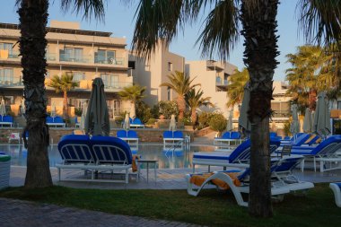 Yüzme havuzu, güneşlik yatakları ve palmiye ağaçları olan lüks bir otelde sakin bir sabah. Seyahat ve eğlence yayınları veya web siteleri için ideal resim