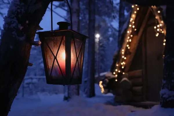 Noel arifesinde Laponya 'da huzurlu bir kutup gecesinde Noel ışıklarıyla süslenmiş bir kulübede parlayan rahat bir fener. Bayram mevsiminin şenlikli cazibesi ve huzurlu büyüsü
