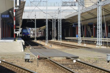 Modern tren istasyonu peronunda birden fazla ray var ve tren kalkışa hazır. Toplu taşımacılık, tren yolculuğu ve yolcu seyahatleri için altyapı