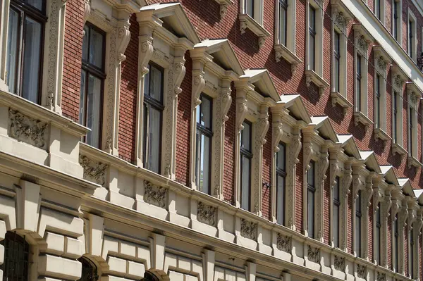 Tarihi bir Avrupa binasının ön cephesinde, mimari ayrıntıların yinelenmesi ve klasik stili üzerine dekoratif vintage pencerelerin ritmik deseni. Şehir dokusunu ve mirasını yakalar