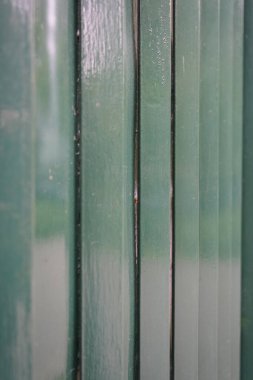 Yeşil boyanmış metal yüzeyin makro detayları soyut dikey çizgileri, tekrarlayan desenleri ve endüstriyel metalik dokuyu vurguluyor..