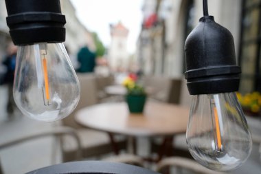 Kaliteli stil LED filament ampulleri kapalı açık havada asılı, bulanık bir kafe veya restoran terası sıcak, davetkar bir ortam yaratıyor