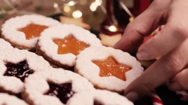 El yapımı Noel kurabiyeleri. Kurabiye tabağını dekore eden bir kadının elleri. Linzer kurabiyeleri. Noel ve Yeni Yıl için Tatil Fırını ve Dekorasyonu