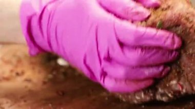 A chef's hand rubs a raw piece of meat with spices