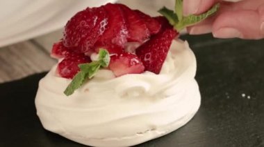 Dessert of meringue with fresh strawberries  and mint. Beautiful serving of dessert in the restaurant. Pavlova's dessert. Close-up of the dessert.