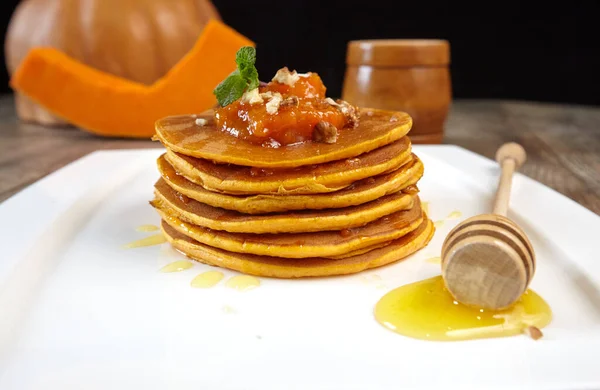 Pancakes with sweet pumpkin and honey close-up on a plate