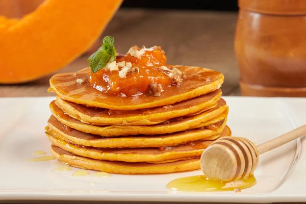 Pancakes with sweet pumpkin and honey close-up on a plate