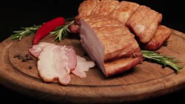 Bir blok dolusu domuz pastırması siyah arka planda tahta bir tahtada dönüyor. Üst görünüm 