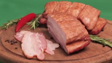 Füme domuz pastırması, yeşil arka planda tahta bir tahtada dönüyor. Üst görünüm 