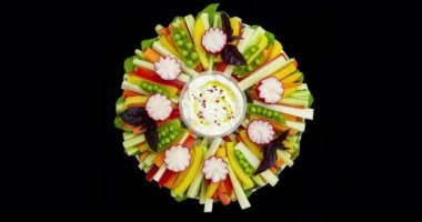 Beyaz soslu bir tabakta dilimlenmiş çiğ sebzeler. Tatil masası için renkli bir dekor, açık büfe. Üst Manzara. Video bir alfa kanalı, şeffaf arkaplan ile çevrilidir