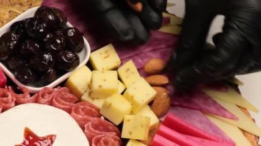 Şef, Haruterie ve peynir tabağını süslüyor. Çeşit çeşit peynirli aperatifler, salam, jambon, zeytin ve fındık. Yakın plan. Üst görünüm 