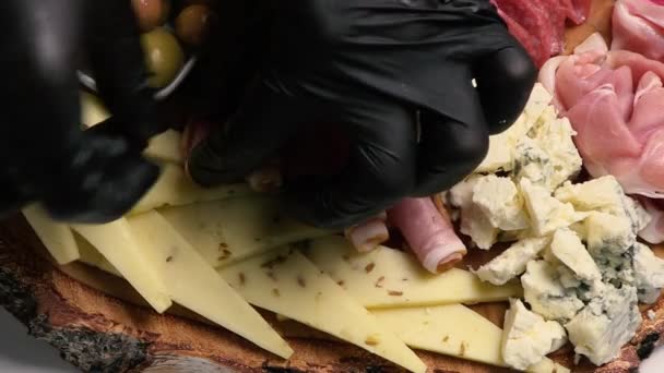シェフはハーカテリーとチーズプレッターを飾っています チーズ サラミ オリーブ ナッツのアペタイザーボード クローズアップ トップビュー — ストック動画
