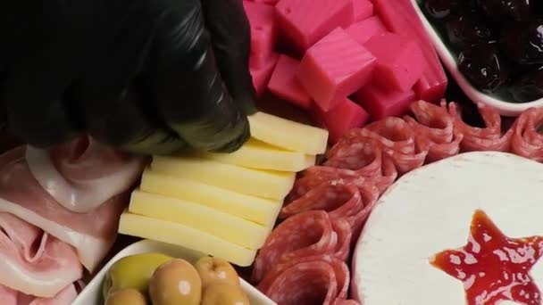 シェフはハーカテリーとチーズプレッターを飾っています チーズ サラミ オリーブ ナッツのアペタイザーボード クローズアップ トップビュー — ストック動画