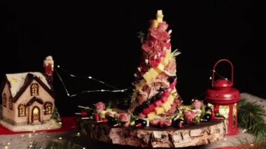 Aperatifler farklı pastalar, şarküteri, atıştırmalıklar ve peynirle servis ediliyor. Noel ağacı et, sosis lezzetleri ve tahtanın üzerinde peynir. Siyah arkaplanda Noel dekoru