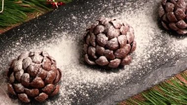 Kar gibi pudra şekeri serpiştirilmiş koni şeklinde çikolatalı kekler. Üst Manzara. Noel ve yeni yıl arifesi için şenlikli pişmiş yiyecekler.