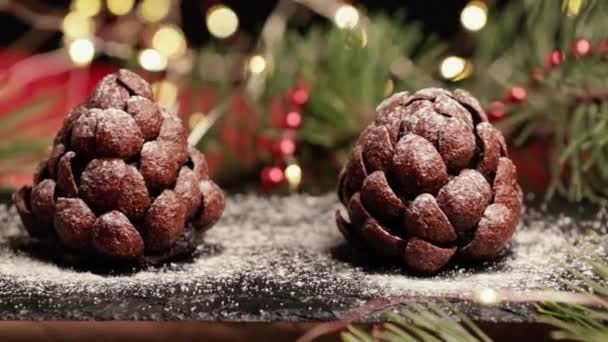手工制作的巧克力甜甜的甜点 形状为冷杉或松果 背景五颜六色 有松枝和闪烁的花环 圣诞及除夕的喜庆烘焙食品 — 图库视频影像