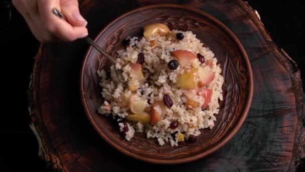 木製板のセラミックプレートにリンゴ サルタナ ドライフルーツが付いている甘い米のお粥 トップビュー シェフは料理を試食する 東洋料理 甘いピラフ — ストック動画