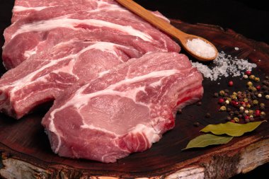 Çiğ taze domuz eti, ahşap bir tahtanın üzerinde baharat ve tuz ile kızartıldığı için parçalara ayrıldı. Yakın plan.