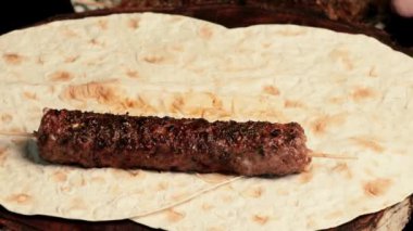 Kebap: Kıyma şiş üzerinde ızgara sosis. Şef onları birbiri ardına pide çarşafına seriyor. Doğu mutfağı.
