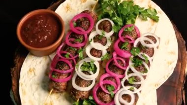 Kebap: ızgara sosis kıymalı et şişi ve pide ekmeği yavaşça ahşap bir tahtanın üzerinde dönüyor. Şef yemeği ince doğranmış otlarla süslüyor. Üst Manzara. Doğu mutfağı.