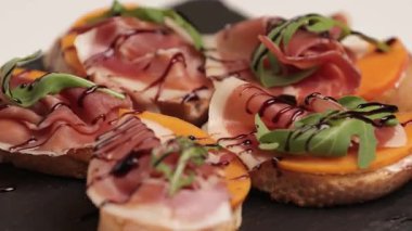 Jambonlu sandviçler, taze tost, iberico. Siyah bir plaka üzerinde dönüyor. Yan görünüm, yakın plan