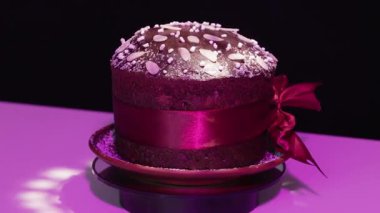 Panettone (Kulich, Paska) renkli bir arka planda toz şeker dekorasyonuyla çikolata hamurundan yapılmıştır. Geleneksel Paskalya ve Noel pastaları. Döngülü video
