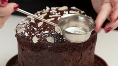 Aşçı panettone 'u pudra şekerle süslüyor. Paskalya ve Noel için pişirme. Bir kadının ellerine yakın çekim