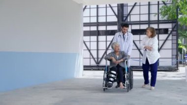 Doktor, hasta ve akrabalar hastane koridorlarında tekerlekli sandalyede yürüyorlar ve anksiyete, tıbbi bakım konsepti, sağlık hizmetleri gibi semptomları tartışıyorlar.