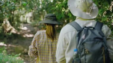 Orman yürüyüşüne çıkan çift biyolog, ağaç tepelerini, koruma kavramını, yeşili ve çevreyi incelemek için dürbün kullanıyor..