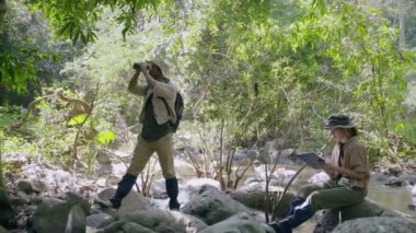 Orman yürüyüşüne çıkan çift biyolog, ağaç tepelerini, koruma kavramını, yeşili ve çevreyi incelemek için dürbün kullanıyor..