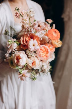 Gelin elinde bir buket çiçek tutuyor.